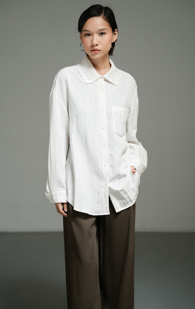 Kemeja wanita lengan panjang warna putih (white chunky open-work crochet shirt top) Ripley Top dengan konstruksi rajut tebal bertekstur, penutup kancing depan, serta saku fungsional bergaya utilitas.