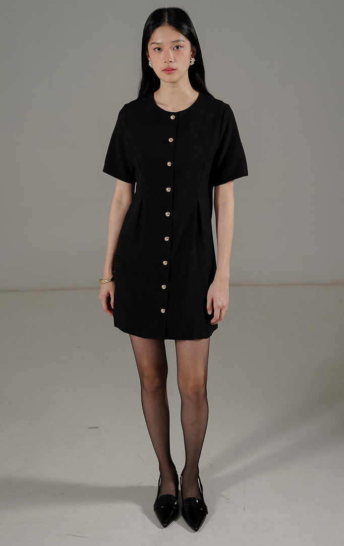 Rolaine Dress Black dari This Is April, gaun pendek warna hitam dengan detail kancing emas aktif di bagian depan bergaya mewah