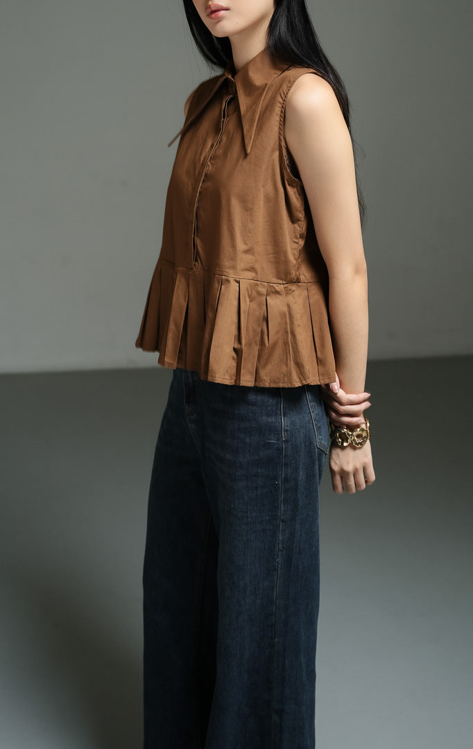 Atasan wanita tanpa lengan model peplum bervolume (exaggerated peplum top) warna cokelat (brown) Serelina Top dari bahan katun poplin terstruktur dengan potongan kerah lancip yang modern.