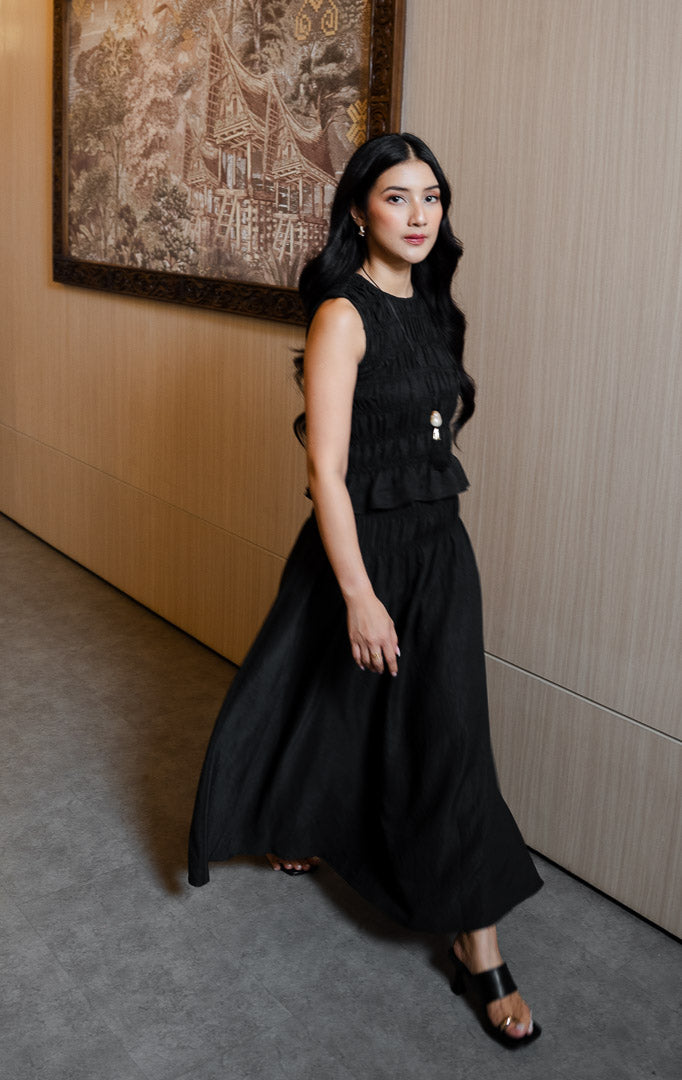 Pakaian atasan wanita model tanpa lengan dengan tekstur kerut smok penuh (all-over shirred smocking) dan potongan peplum anggun warna hitam SF Norielle Top untuk gaya kantor dan kasual elegan.
