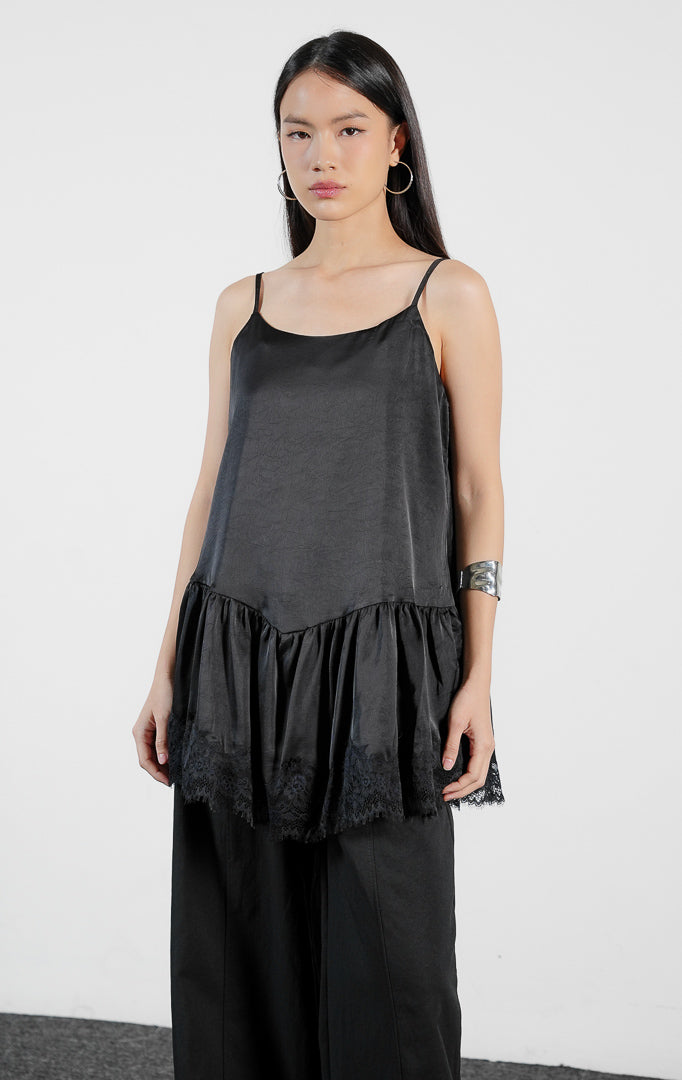Pakaian wanita model atasan kamisol tali spageti bahan poliester dengan detail lapisan bertingkat dan aksen renda di bagian bawah (tiered flounce hem camisole top) warna hitam Velicia Top untuk gaya kasual feminin.