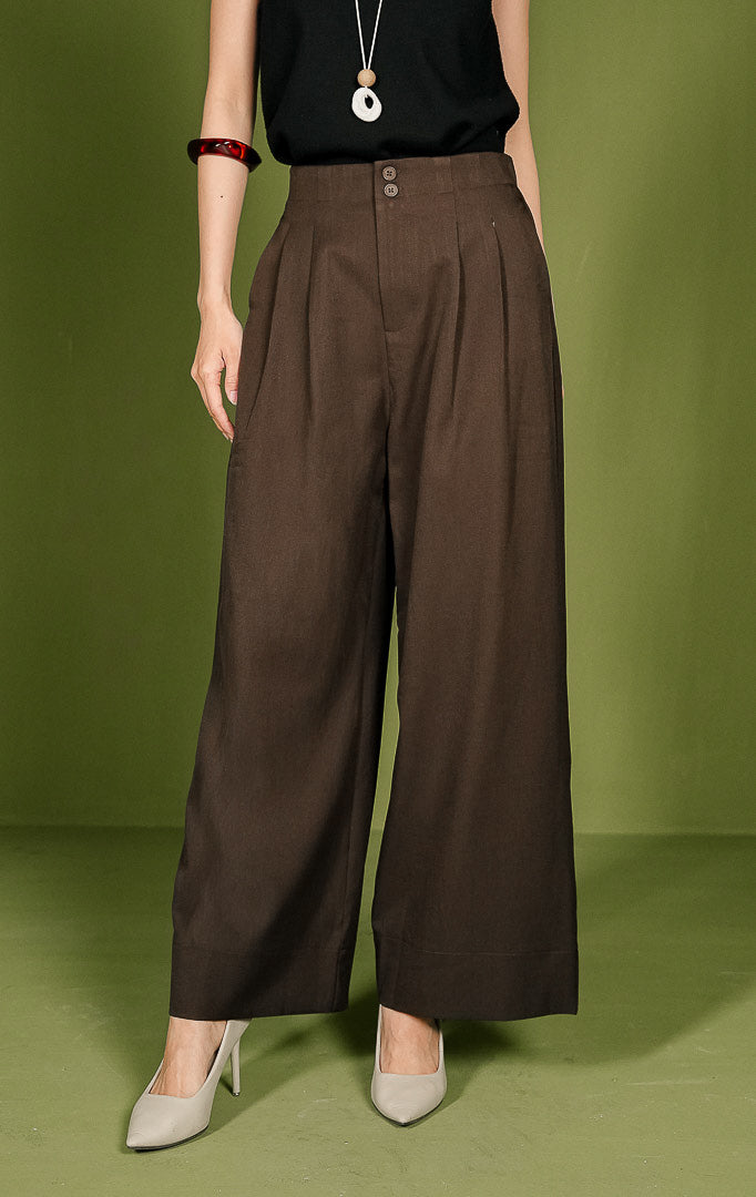 Celana panjang wanita Vincent Pants berpotongan lurus (straight cut) warna cokelat, dilengkapi detail dua kancing bersusun (double button) di ban pinggang depan, aksen lipatan (pleats), saku samping, dan karet elastis di pinggang bagian belakang.