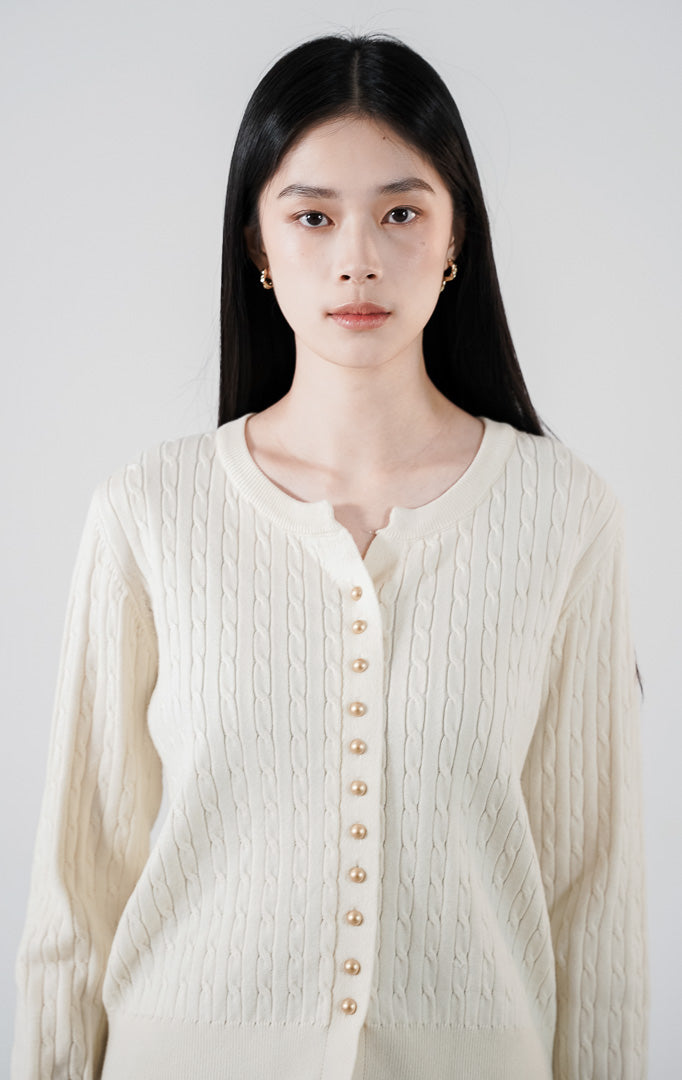 Vinnie Cardigan warna ivory, kardigan rajut kabel (cable knit) lengan panjang dengan detail kancing emas, dipadukan dengan rok plisket cokelat1