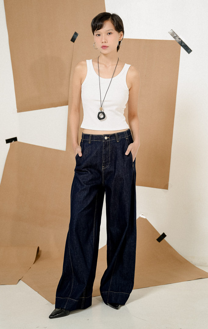 Model berdiri dengan tangan di saku mengenakan Vireya Baggy Denim Pants Dark Denim, produk celana jeans wanita model loose baggy warna biru tua dengan detail jahitan kontras.