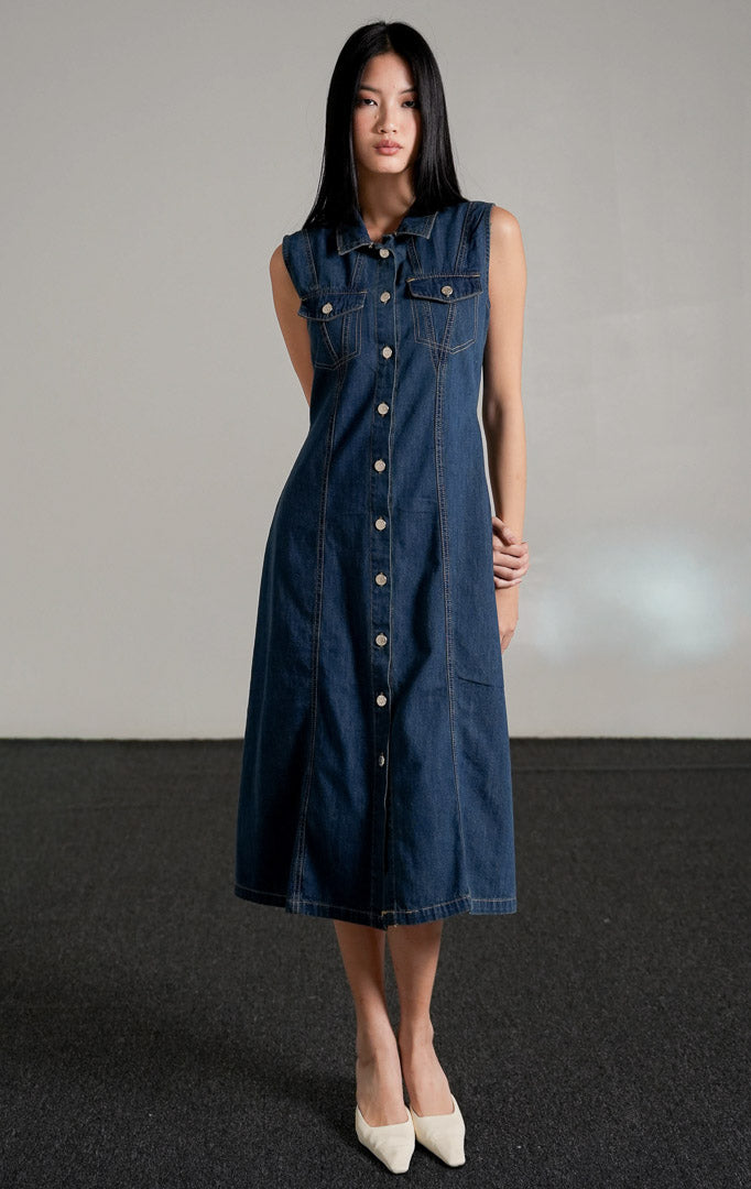 Vivienne Dress Dark Denim, gaun jeans tanpa lengan warna biru tua dengan kerah kemeja dan kancing perak di bagian depan.