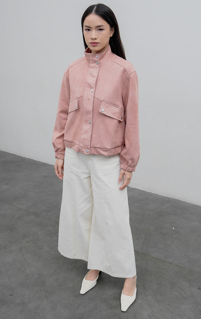Jaket wanita berbahan suede warna merah muda pudar (dusty pink) Woolridge Jacket dengan kerah tinggi (high neck), saku dada fungsional, dan bukaan kancing jepret (snap buttons).