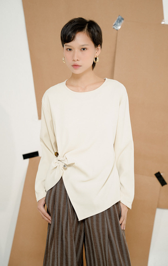 Close-up detail kerutan di bagian depan Wynston Stone-Detail Ruched Blouse Ivory, menampilkan blouse wanita warna putih gading dengan aksen serut dan detail batu dekoratif.