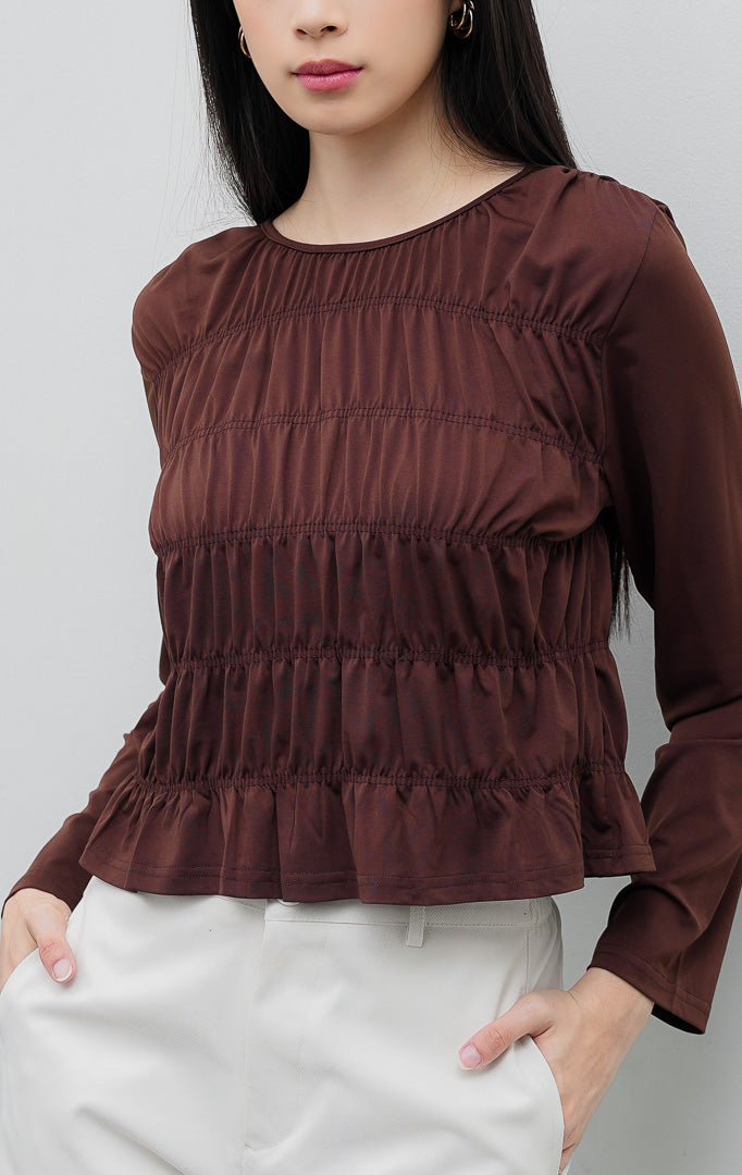Atasan blus wanita lengan panjang warna cokelat tua (dark brown) Yuliana Top berbahan jersey stretch dengan aksen dada kerut (smocked bodice) dan kancing belakang.