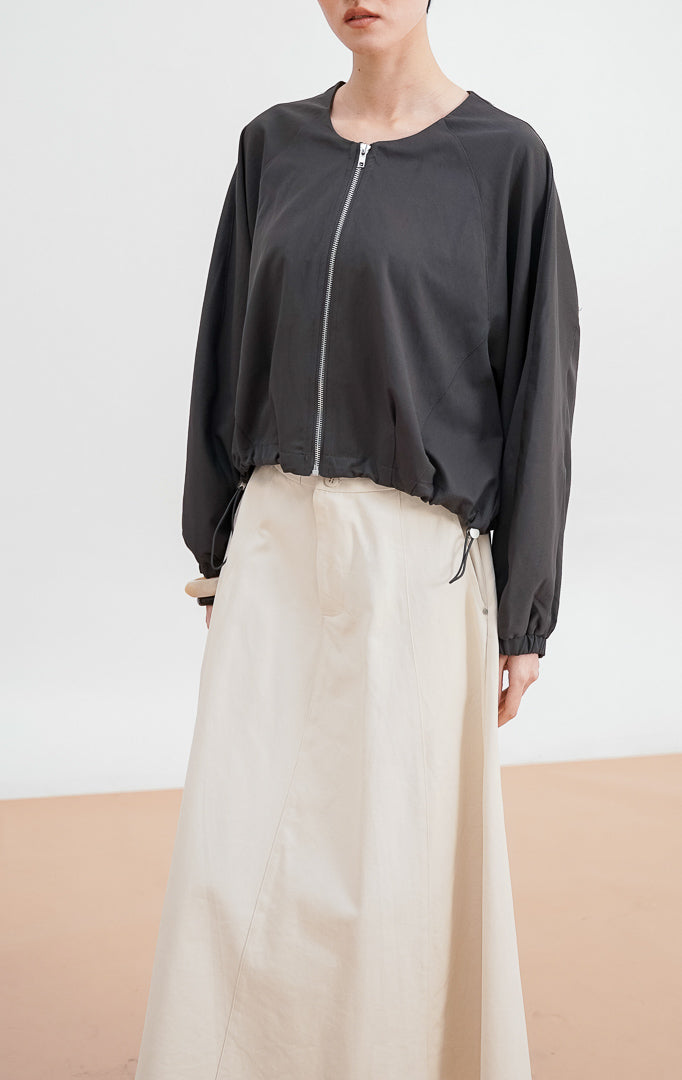 Model berpose mengenakan Zoria Jacket warna dark grey, jaket zip-up dengan siluet lengan balloon, kerah bulat, dan detail pergelangan tangan elastis