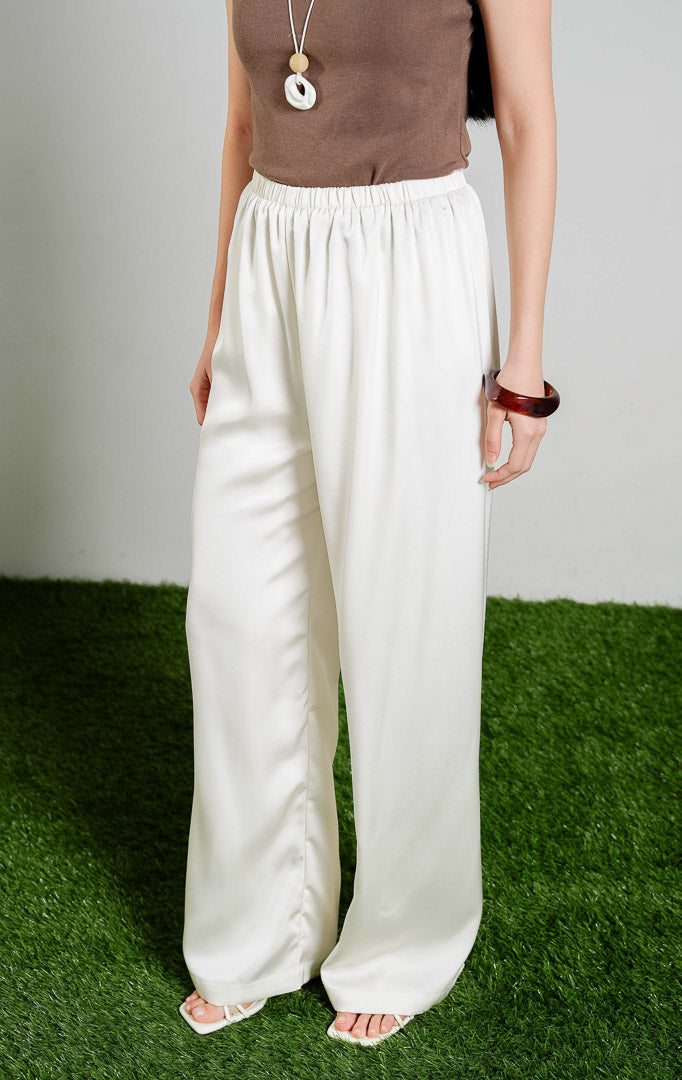 Theodore Relaxed Satin Loose Pants warna ivory, celana panjang kulot wanita bahan satin mengilap dengan karet pinggang warna putih gading dari This Is April. 