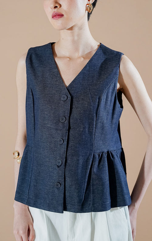 Agatha Vest Indigo dari This Is April, rompi tanpa lengan wanita warna biru indigo dengan kancing depan, leher V-neck, dan detail ruffle di bagian bawah.