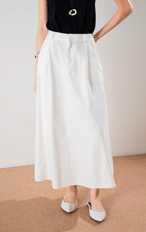 Tampilan bawah rok panjang Almira Skirt White dengan detail lipit depan, kancing, dan saku, dipadukan dengan atasan hitam dan sepatu flat putih.