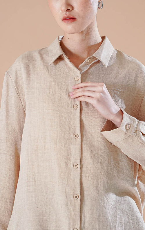 Kemeja basic lengan panjang berkerah Carolina Top berwarna khaki berbahan katun bertekstur, dipadukan dengan celana pendek denim dan sepatu flat putih