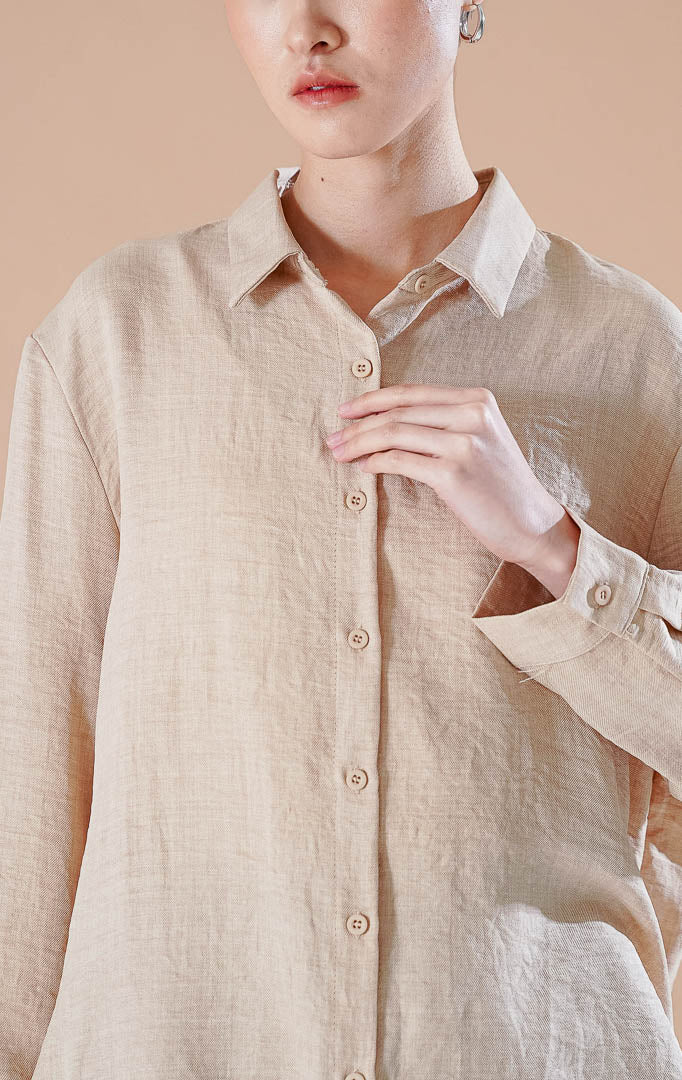 Kemeja basic lengan panjang berkerah Carolina Top berwarna khaki berbahan katun bertekstur, dipadukan dengan celana pendek denim dan sepatu flat putih