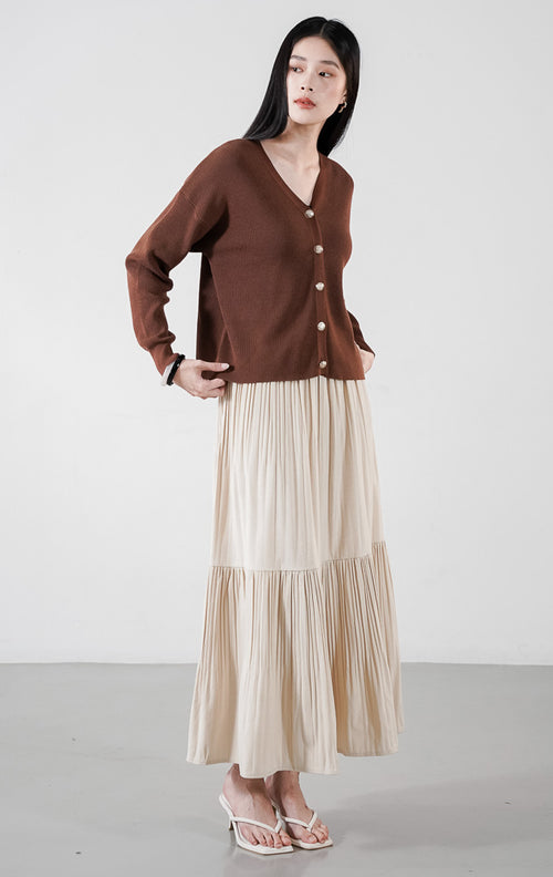  Delphine Cardigan warna dark brown, kardigan rajut V-neck lengan panjang dengan kancing emas bulat, dipadukan dengan rok plisket krem.