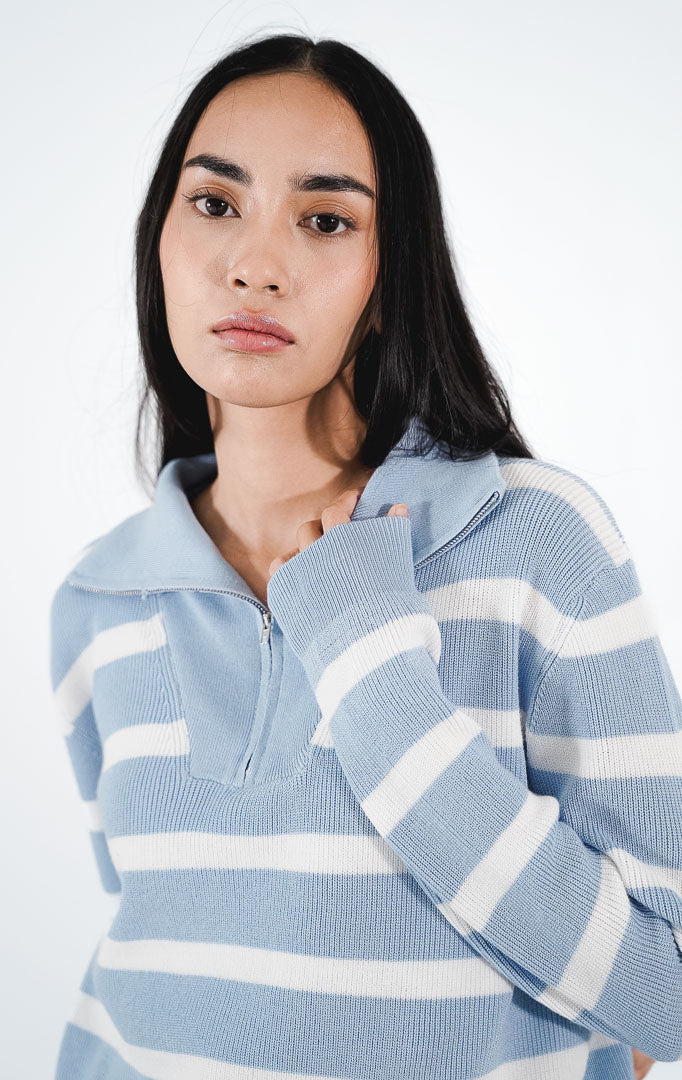 Ellis Sweater warna baby blue, sweater rajut lengan panjang dengan motif garis horizontal putih dan detail kerah tinggi beresleting (half-zip).