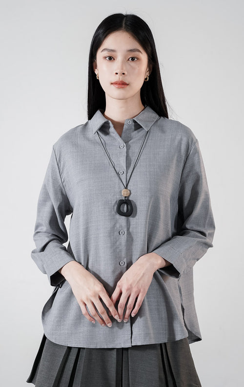  Fabienne Top warna grey, kemeja katun slub lengan panjang dengan kerah klasik dan kancing depan, dipadukan dengan rok plisket abu-abu.1