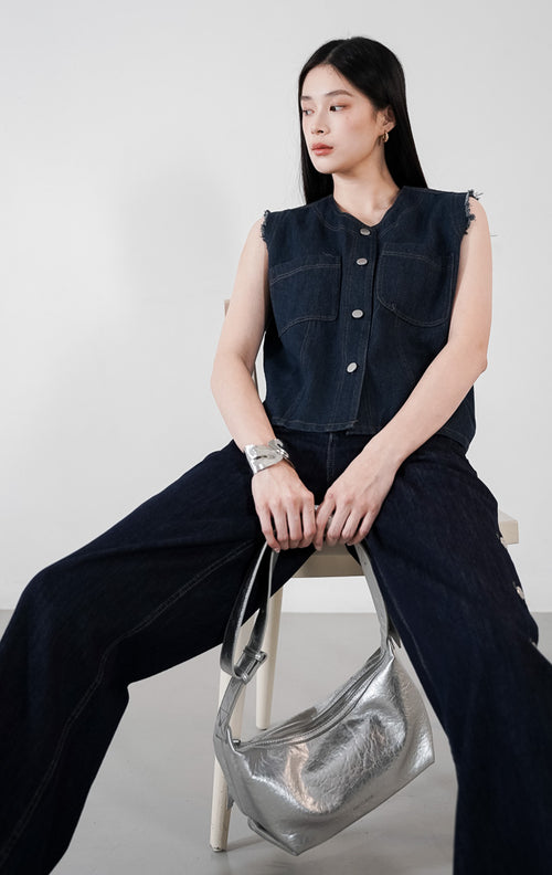 Marais Vest warna indigo denim, rompi jeans tanpa lengan dengan detail ujung lengan rawis, saku ganda di dada, dan kancing perak depan.