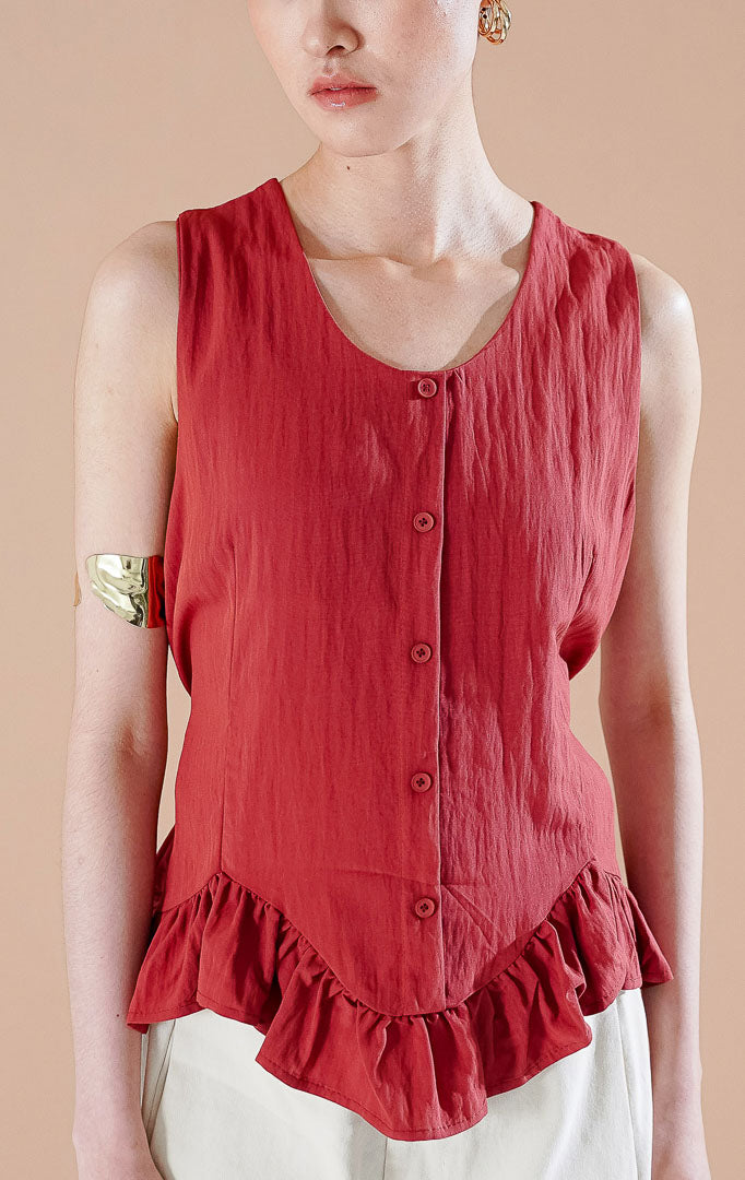 Atasan wanita Odellia Top warna Terracotta dengan detail peplum rampel, kancing depan aktif, dan tali samping yang dapat disesuaikan untuk gaya kasual elegan