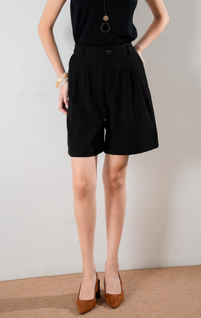Oliver Pants Black, celana pendek hitam tailored dengan siluet terstruktur, dipadukan dengan tank top hitam dan heels cokelat