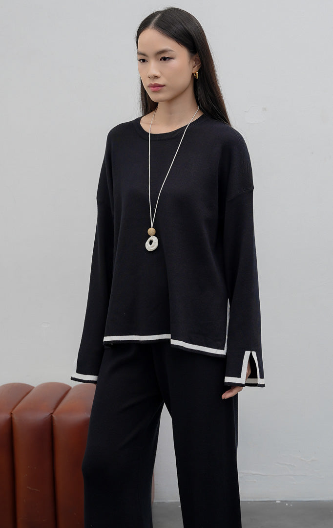 Setelan wanita atasan dan bawahan berbahan rajut lembut (soft stretchy knit) warna hitam dengan motif garis (striped pattern), detail belahan samping (subtle slit), dan pinggang karet elastis.