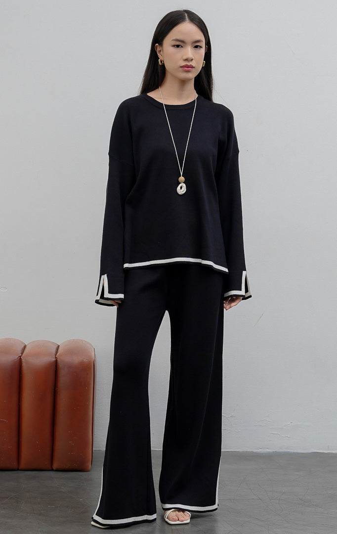 Setelan wanita atasan dan bawahan berbahan rajut lembut (soft stretchy knit) warna hitam dengan motif garis (striped pattern), detail belahan samping (subtle slit), dan pinggang karet elastis.