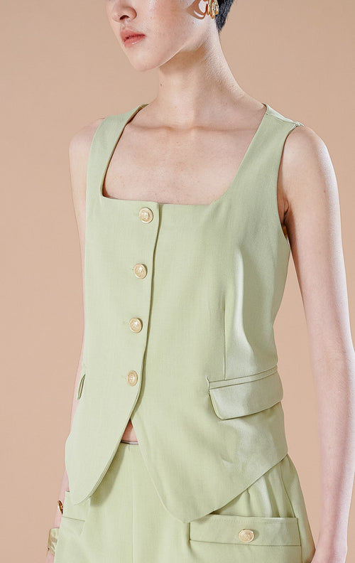 Setelan wanita Pepper Set warna Sage Green yang terdiri dari blazer tanpa lengan terstruktur dengan kancing depan dan celana pendek senada.