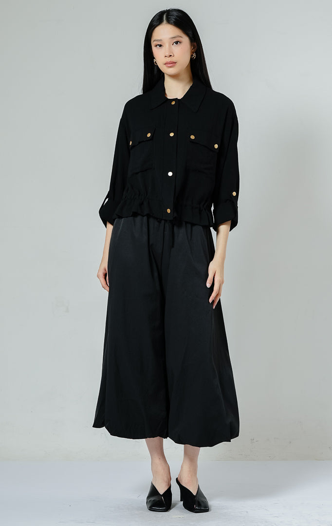 Kemeja utility wanita warna hitam (black) Piyora Top berbahan cotton linen dengan dua saku depan (dual pockets), tali pengikat lengan (roll-up sleeve straps), dan tali serut bagian bawah (drawstring hem).