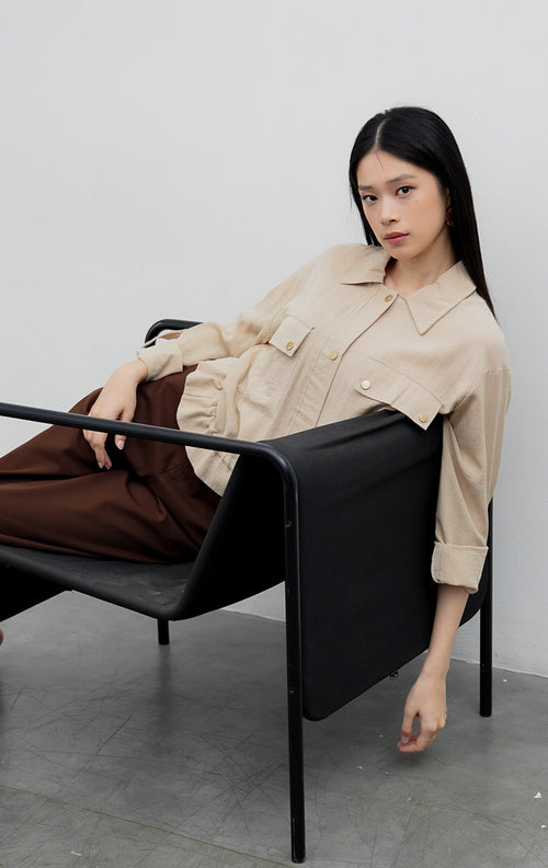 Kemeja utility wanita warna khaki Piyora Top berbahan cotton linen dengan dua saku depan (dual pockets), tali pengikat lengan (roll-up sleeve straps), dan tali serut bagian bawah (drawstring hem).