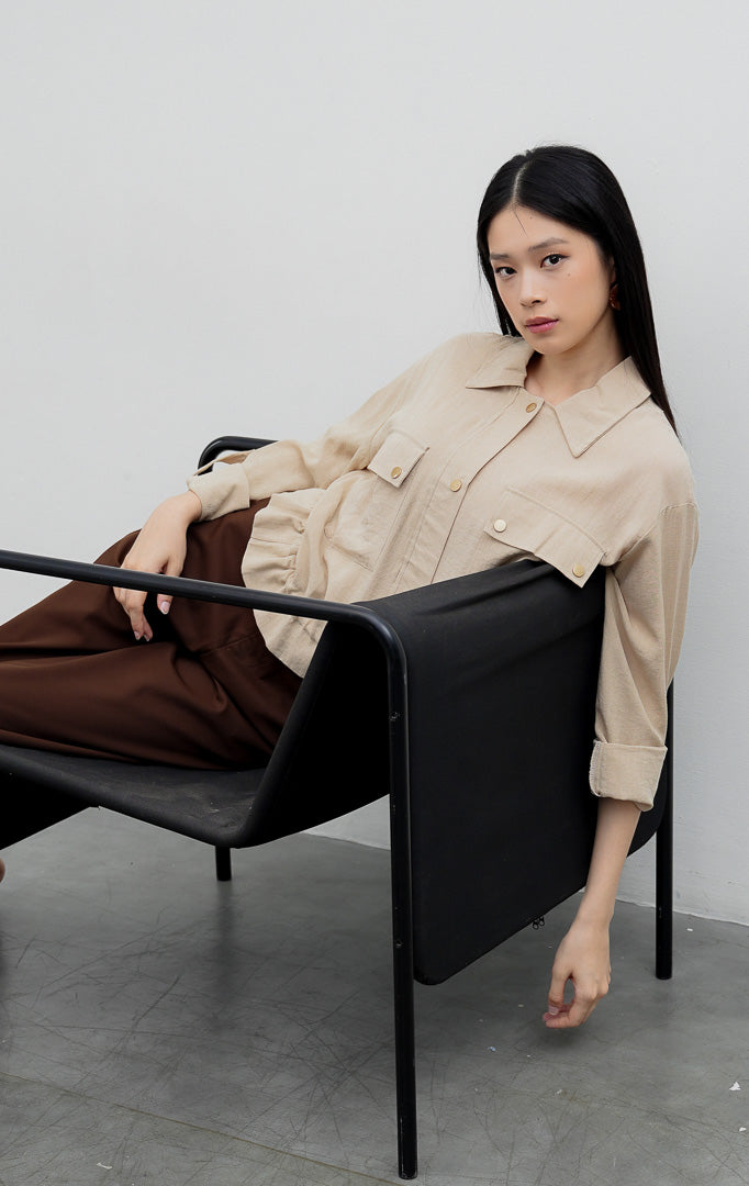 Kemeja utility wanita warna khaki Piyora Top berbahan cotton linen dengan dua saku depan (dual pockets), tali pengikat lengan (roll-up sleeve straps), dan tali serut bagian bawah (drawstring hem).