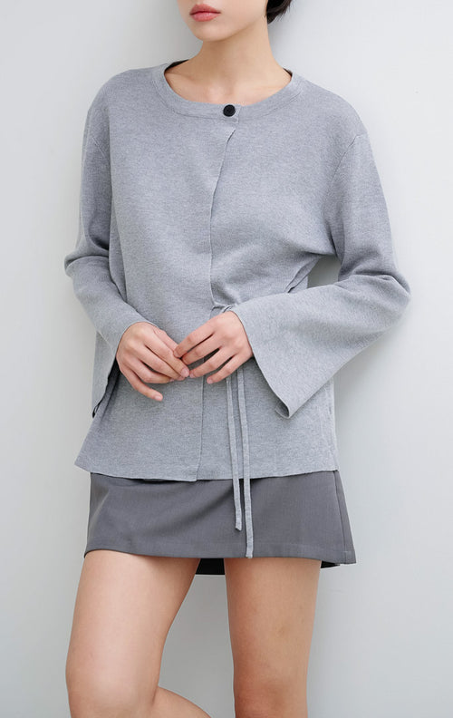 Cardigan rajut wanita warna abu-abu Addison Cardigan This Is April dengan siluet wrap, detail tali samping (side tie), kerah bulat, dan kancing dekoratif di bahu.