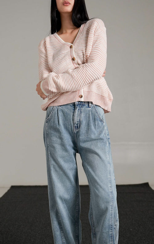 Tampak depan model wanita mengenakan Aderyn Two-Tone Knit Cardigan warna pink dengan kerah v-neck dan kancing depan, dipadukan dengan celana jeans longgar.