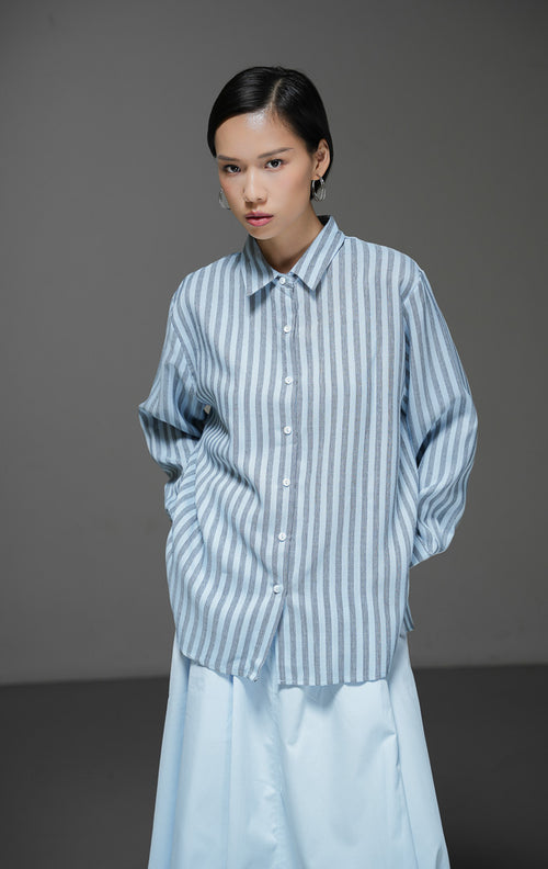 Kemeja wanita Adrienne Top warna biru dengan motif garis salur vertikal (stripe), lengan panjang, kerah kemeja, dan kancing depan. 