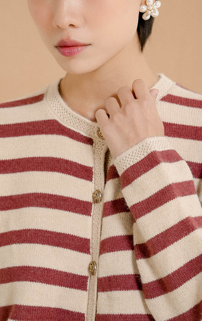 Close up model mengenakan Agatha Striped Gold Button Knit Cardigan Maroon, outerwear cardigan rajut wanita motif garis merah marun dan krem dengan detail kancing emas. 
