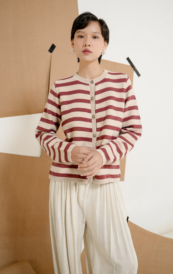 Close up model mengenakan Agatha Striped Gold Button Knit Cardigan Maroon, outerwear cardigan rajut wanita motif garis merah marun dan krem dengan detail kancing emas. 
