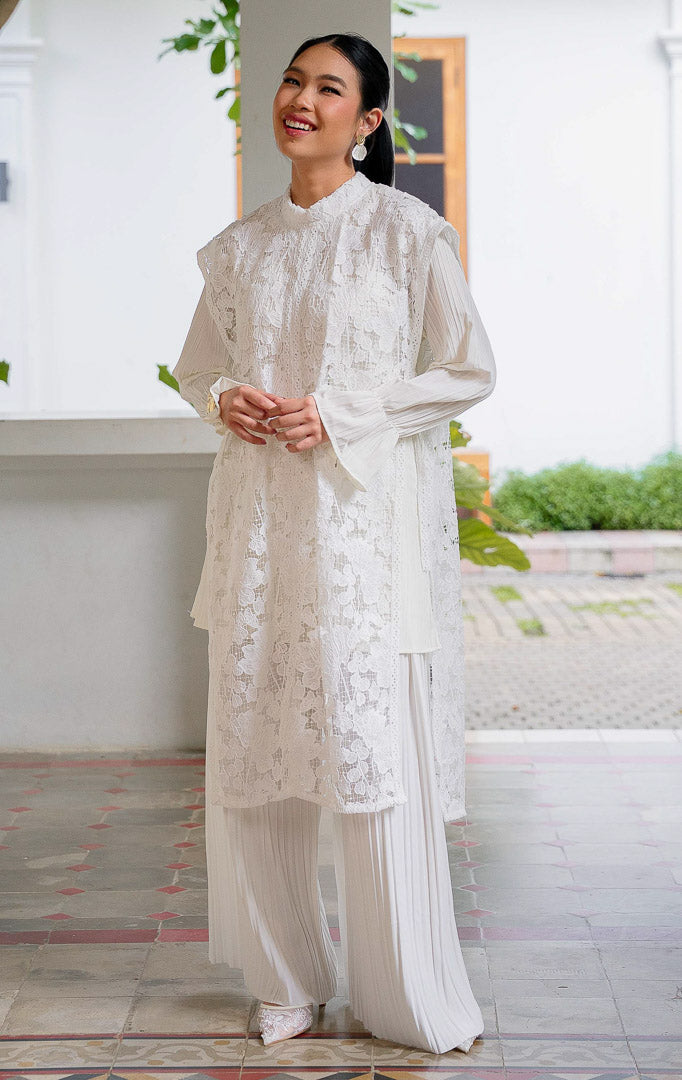 Aleeya Outer White, rompi panjang wanita bahan lace motif bunga warna 
putih dengan kerah tinggi dan detail transparan yang cocok untuk layering.