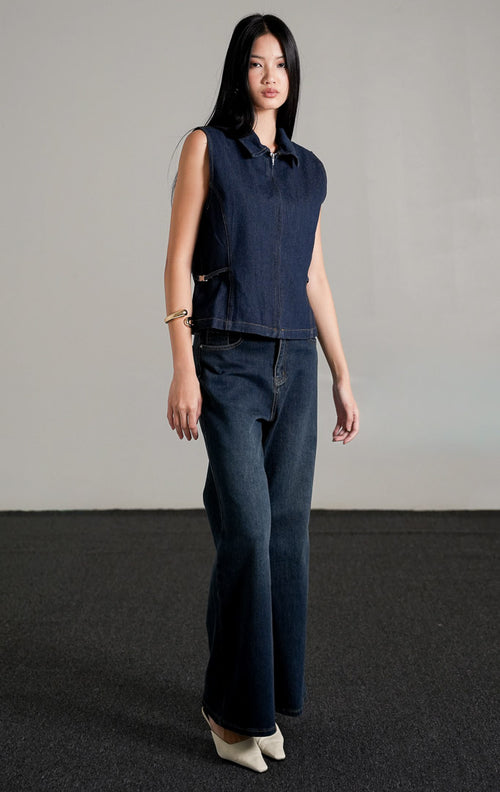 Alice Vest Indigo, sebuah rompi denim tanpa lengan berwarna biru dongker dengan kerah, dipadukan dengan celana jeans panjang senada.