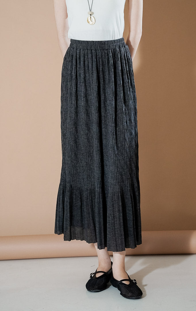 Wanita mengenakan rok maxi plisket Allison Skirt berwarna Dark Grey dengan potongan flowy yang elegan dari This Is April.