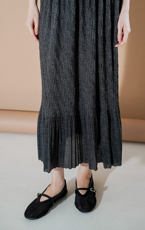 Wanita mengenakan rok maxi plisket Allison Skirt berwarna Dark Grey dengan potongan flowy yang elegan dari This Is April.