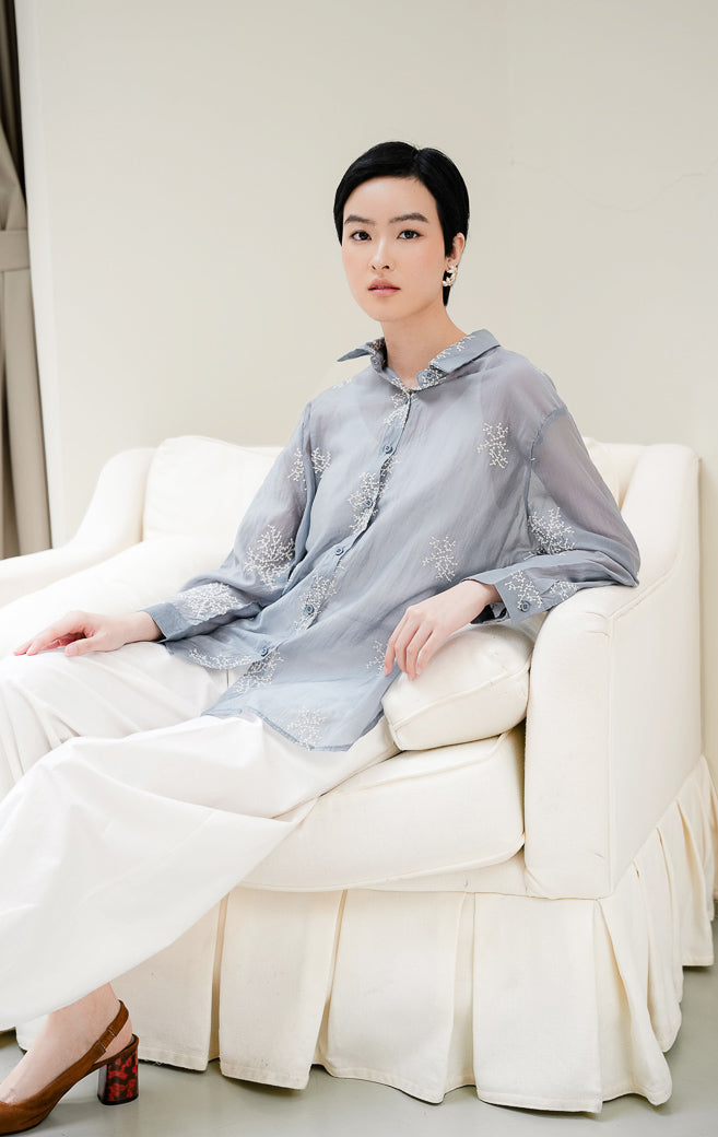 Atasan kemeja wanita Amaranth Top warna dusty blue berbahan cotton voile transparan (sheer) dengan motif bordir (embroidery) dan kancing depan style feminine & elegant. 