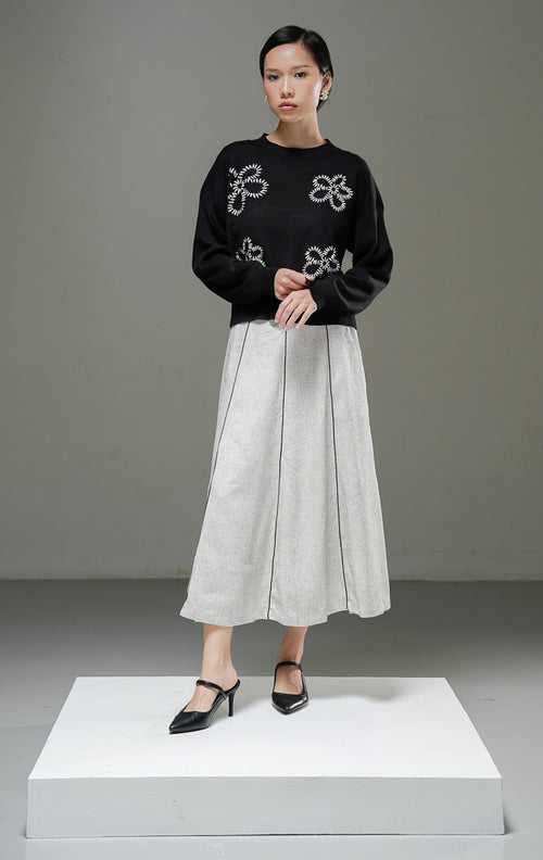 Sweater rajut wanita Amora Sweater warna hitam lengan panjang dengan motif bordir bunga besar, kerah bulat, dan detail ribbed hem. 