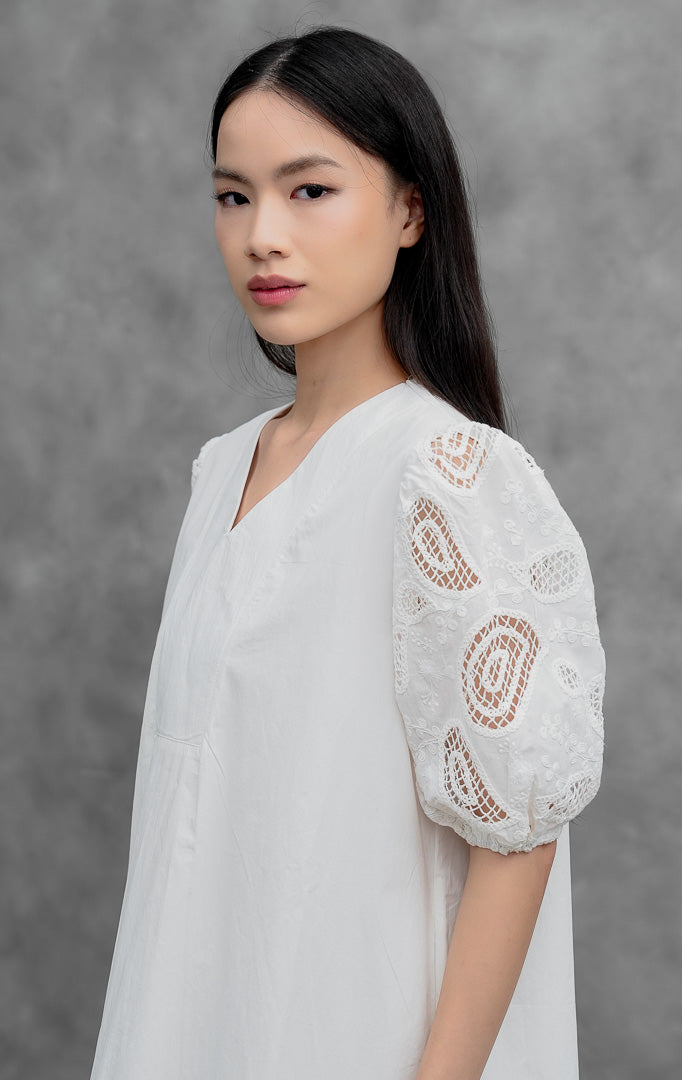 Gaun terusan wanita model midi warna putih (white) Anatolia Dress berpotongan A-line dengan aksen bordir berlubang (eyelet detailing) dan lengan balon (puff sleeves).