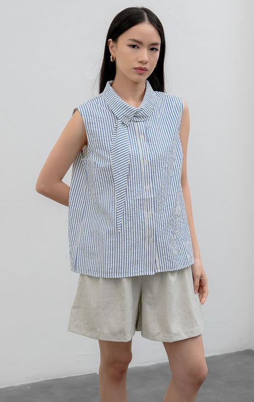 Atasan sleeveless blouse wanita warna biru (blue) Anestassia Top bermotif garis vertikal (striped) berbahan crinkle polyester dengan aksen kerah draped dan tali ikat (tie detail).