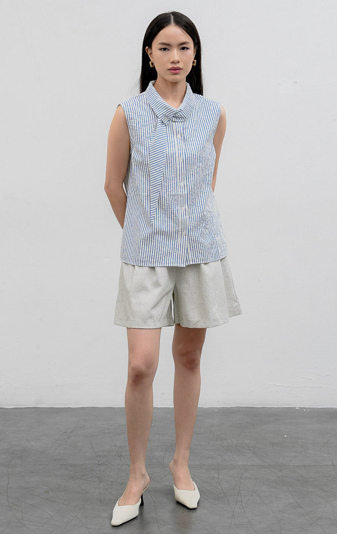 Atasan sleeveless blouse wanita warna biru (blue) Anestassia Top bermotif garis vertikal (striped) berbahan crinkle polyester dengan aksen kerah draped dan tali ikat (tie detail).