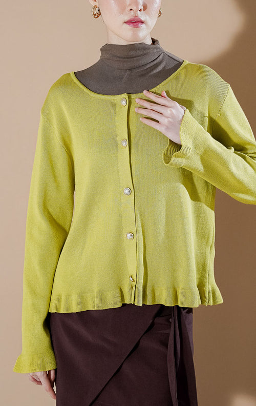 Model wanita mengenakan Angelita Cardigan berwarna Lime (hijau kekuningan) dengan detail ruffle di bagian pinggir dan kancing emas yang elegan dari This Is April.