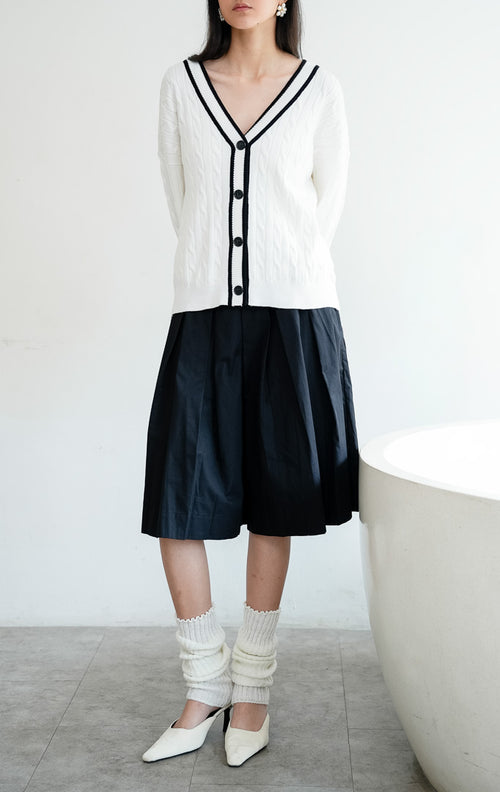 Kardigan rajut wanita lengan panjang warna putih (white) Annette Cardigan bermotif rajut kepang (cable knit) dengan lis kontras di leher V (V-neckline) dan bukaan kancing depan.