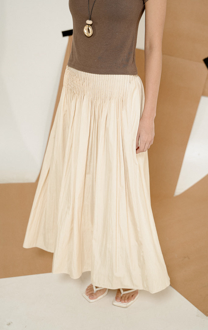 Close up detail pinggang karet elastis dan jahitan rempel dari Annora Skirt Yellow, produk rok maxi panjang wanita warna kuning pastel lembut dipadukan dengan atasan cokelat. 