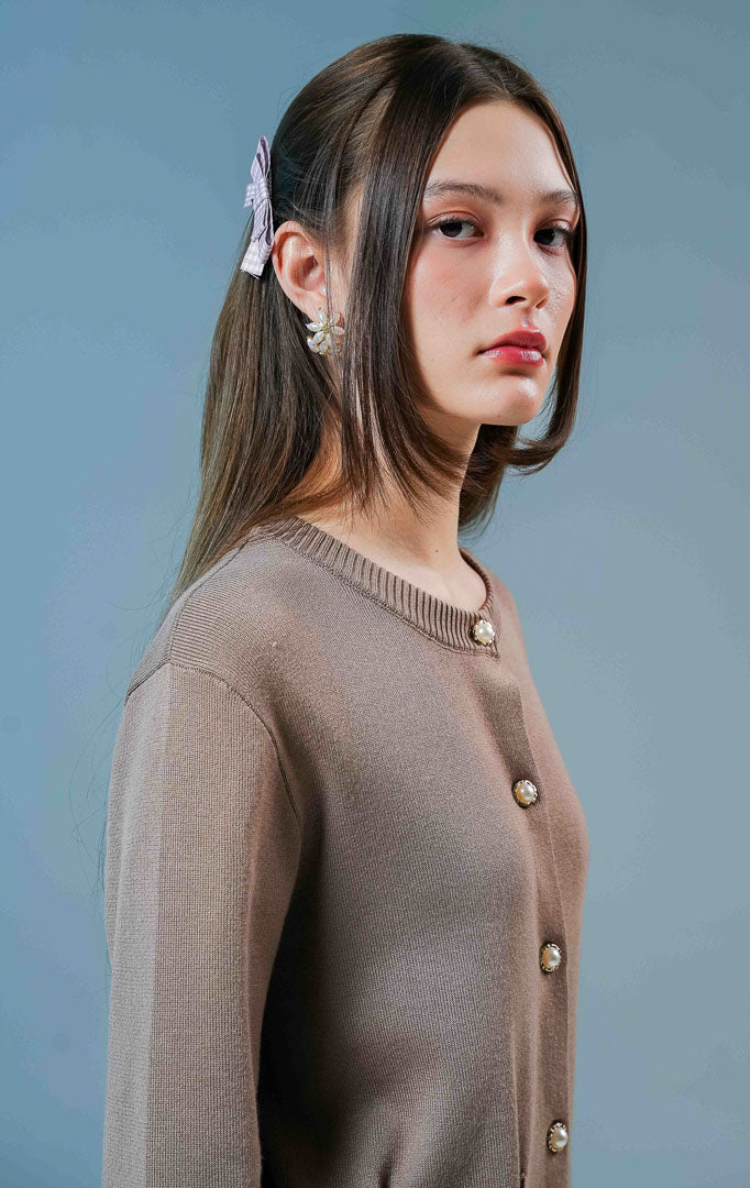 Model wanita mengenakan Ellington Knit Cardigan warna coklat muda, luaran rajut wanita berkerah bulat dengan detail kancing depan elegan dan saku. 