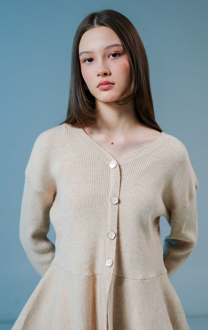 Model wanita mengenakan Eulalie Ribbed Peplum Knit Cardigan warna khaki, luaran rajut wanita lengan panjang bertekstur rib dengan detail kancing depan dan siluet peplum yang feminin. 