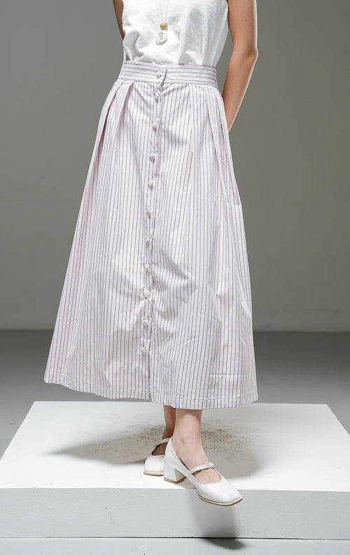 Rok midi wanita Artemis Skirt warna light pink merah muda lembut motif salur garis vertikal dengan kancing depan berlaput kain, detail pleat, dan pinggang karet. 
